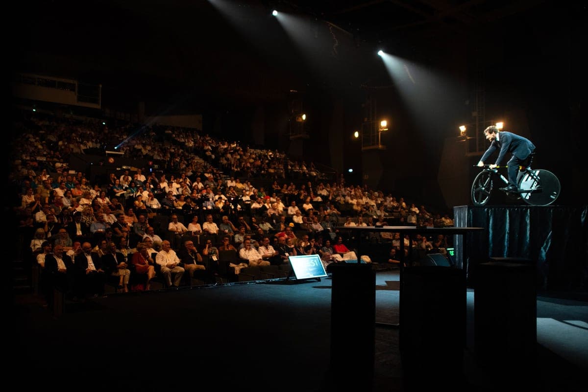 Clément en keynote dans un amphithéâtre sombre — lumière de scène, public